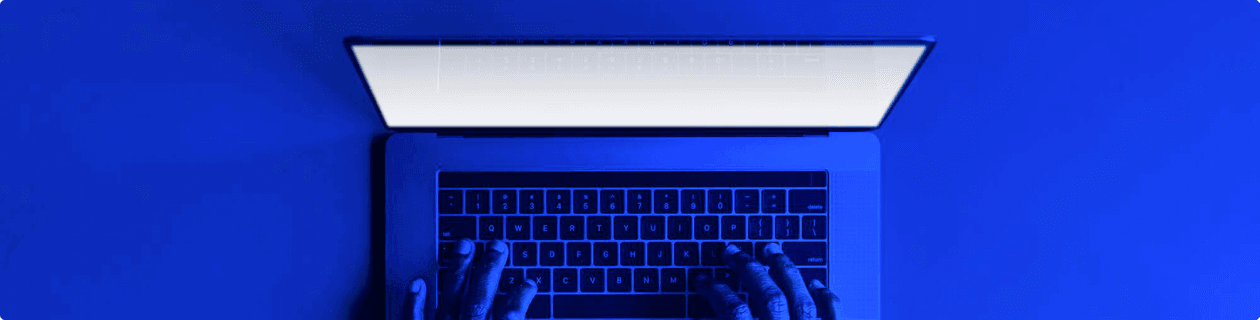 Hands typing on a laptop with blue lighting